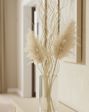 Load image into Gallery viewer, Decorative arrangement of dried plants in a clear vase against a neutral wall.