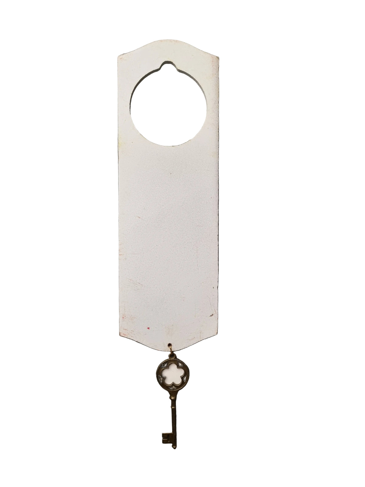 A white wooden door hanger with a circular cutout at the top and a vintage-style metal key hanging from the bottom, displayed against a white background