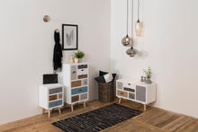 Load image into Gallery viewer, A styled interior scene showing three white storage cabinets with multiple drawers in blue, beige, brown, and gray, arranged on a wood floor against white walls with hanging pendant lights and decor.