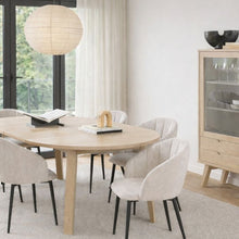 Load image into Gallery viewer, Dining room with a round wooden table and beige chairs, featuring a large window and a cabinet.