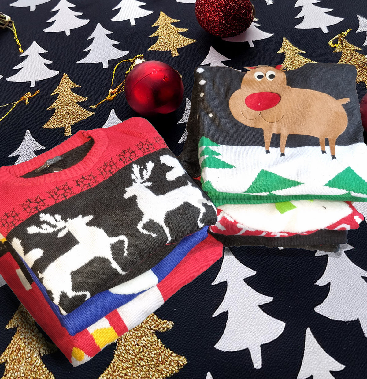 A stack of folded Christmas-themed knit sweaters displayed on a dark holiday-patterned fabric background with red and gold ornaments. The top sweater features a reindeer design, and other folded sweaters underneath show red, blue, white, and yellow holiday patterns.
