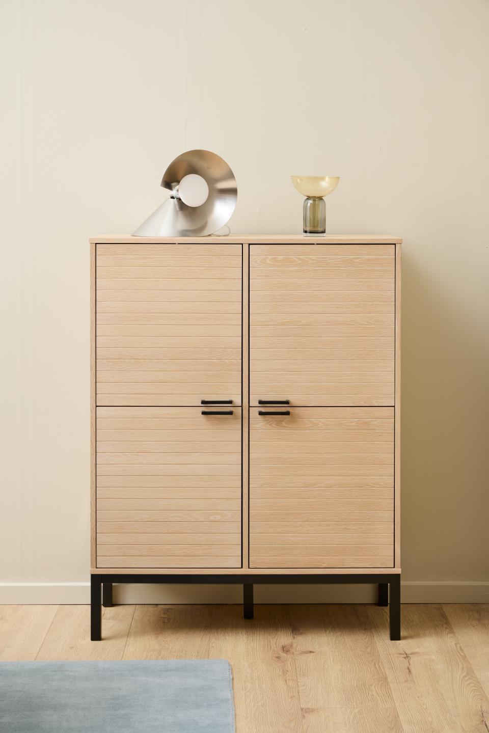 Wooden cabinet with two doors on a wooden floor against a beige wall.