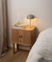 Load image into Gallery viewer, Wooden bedside table with a lamp, book, and candle next to a bed.