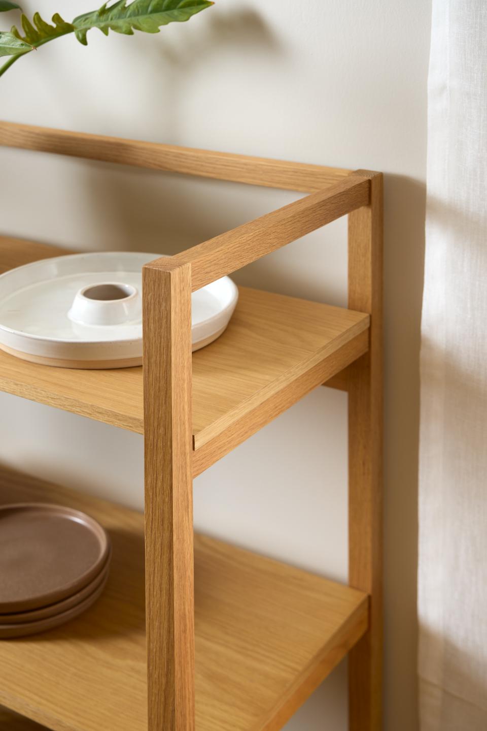 Wooden shelf with ceramic plates against a white wall