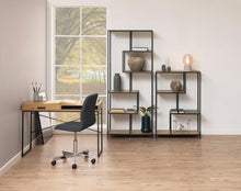 Load image into Gallery viewer, A modern home office setup featuring a light wood desk with a black metal frame, a black swivel office chair, and a matching black metal shelving unit with wood shelves. The room has light wood floors, beige walls, and a large window showing a tree view.