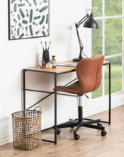 Load image into Gallery viewer, A modern home office setup featuring a desk with a light wood top and black metal frame, paired with a brown leather swivel chair. A black adjustable desk lamp, a woven basket, and a window view are also visible.