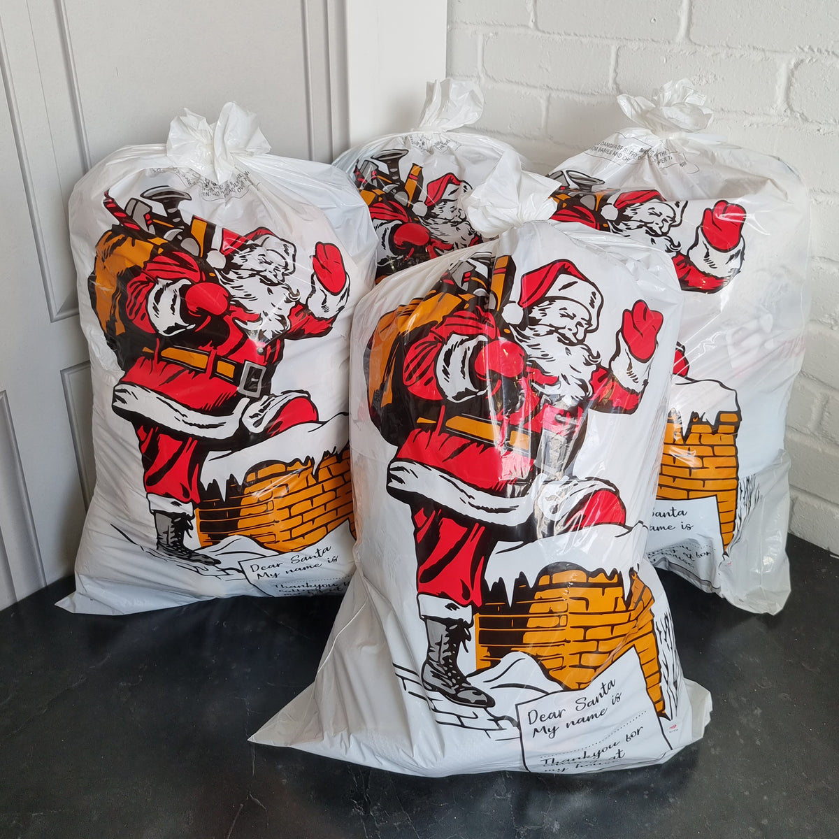 4 Santa sacks filled with presents in the corner of a room