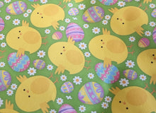 Load image into Gallery viewer, Easter-themed wrapping paper with yellow chicks, colorful eggs, and flowers on a green background.
