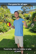 Load image into Gallery viewer, Man holding two colorful objects in a garden setting
