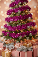 Load image into Gallery viewer, A decorated Christmas tree wrapped in bright metallic magenta tinsel garlands, with warm white string lights, surrounded by pink and gold gift boxes with white faux snow accents against a soft glowing bokeh background.
