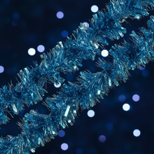 Load image into Gallery viewer, Blue metallic tinsel garland photographed diagonally against a dark blue background with soft white bokeh lights.
