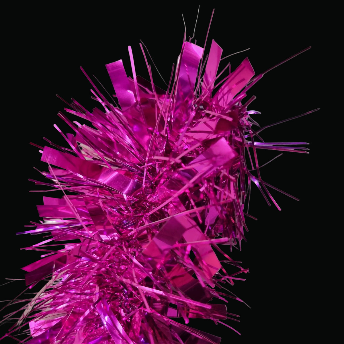 Metallic hot pink tinsel garland with shiny rectangular strips and fine strands, photographed against a plain light gray background.