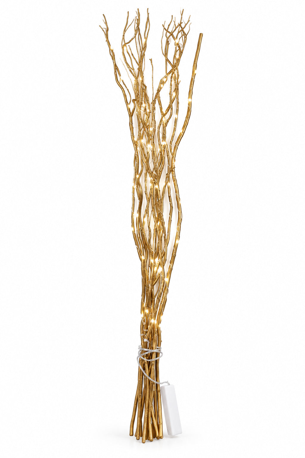 A decorative wall-hanging branch sculpture made of many thin gold-toned branches, lit with small warm white fairy lights, tied near the base with a white string and a small white tag hanging from it, set against a plain white wall.