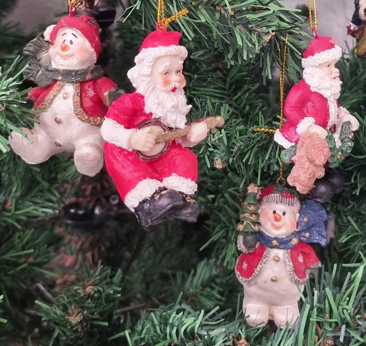 A group of Christmas ornaments shaped like Santa Claus and a snowman, displayed on a Christmas tree