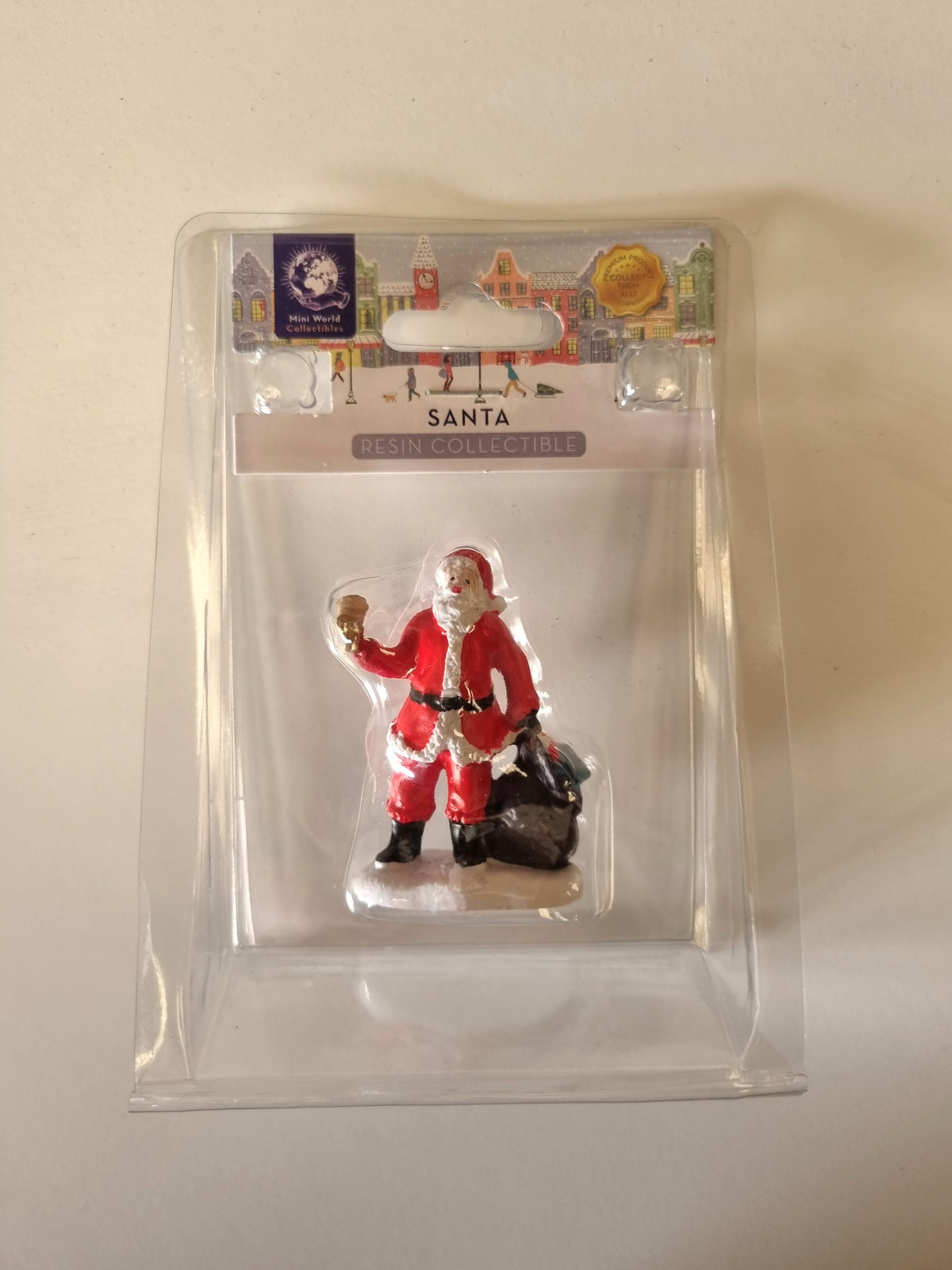 A Santa Claus resin collectible figure inside a clear plastic blister pack with a printed header card, photographed against a plain off-white background.