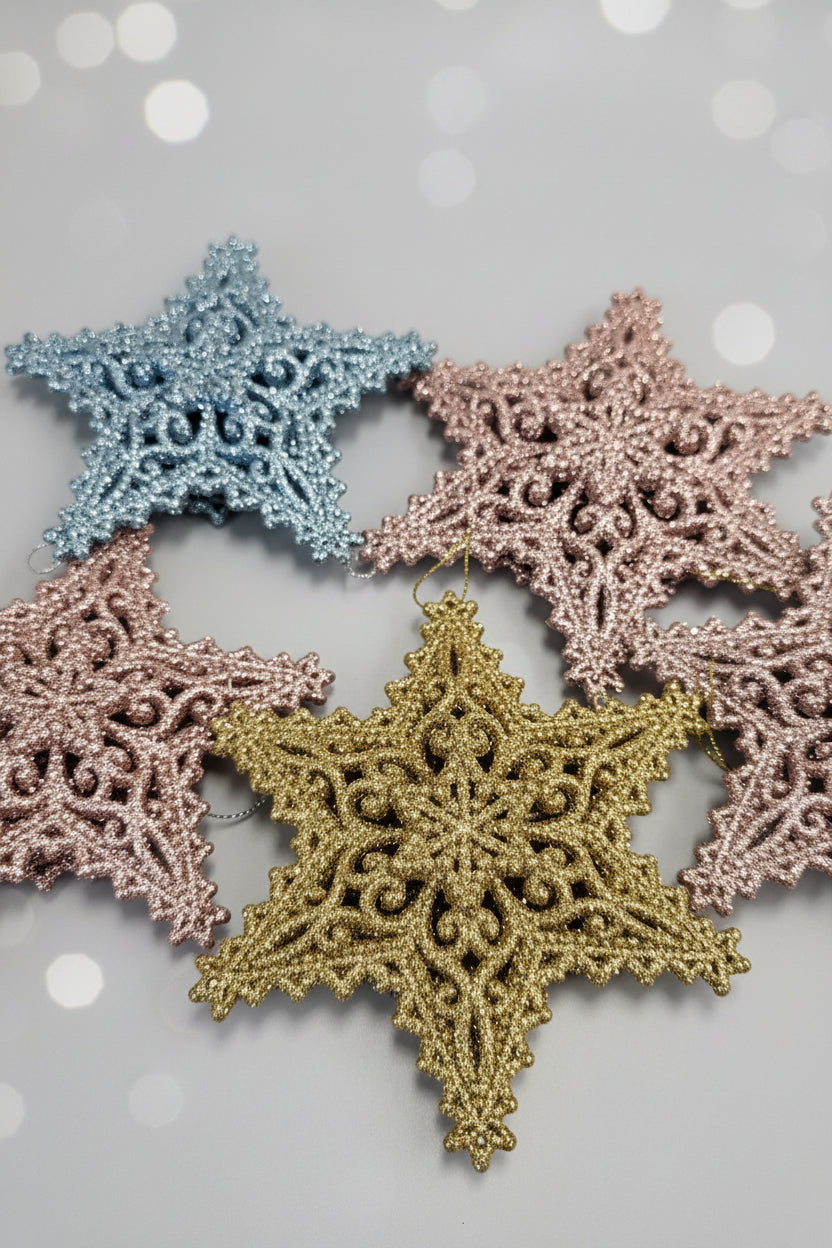 Close-up of several glittery snowflake ornaments in silver, blue, red, and gold arranged on a wooden surface.