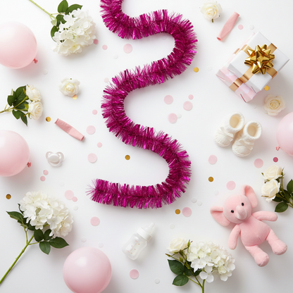 an image showing baby items such as a pink elephant, pink tinsel, bootees and flowers on a table depicting a baby shower celebration