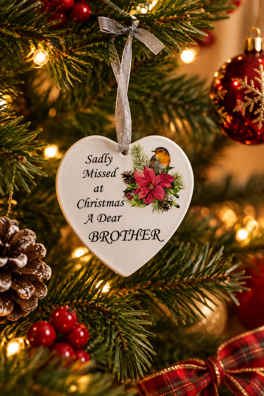 a memorial glass heart with a robin on the front and the message 'sadly missed at Christmas a dear BROTHER' with ribbon attached for hanging all on a Christmas tree