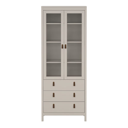 A tall, narrow storage cabinet in a light warm gray or beige finish, featuring two upper glass doors with dark metal handles and four lower drawers with matching handles, set against a plain white background.