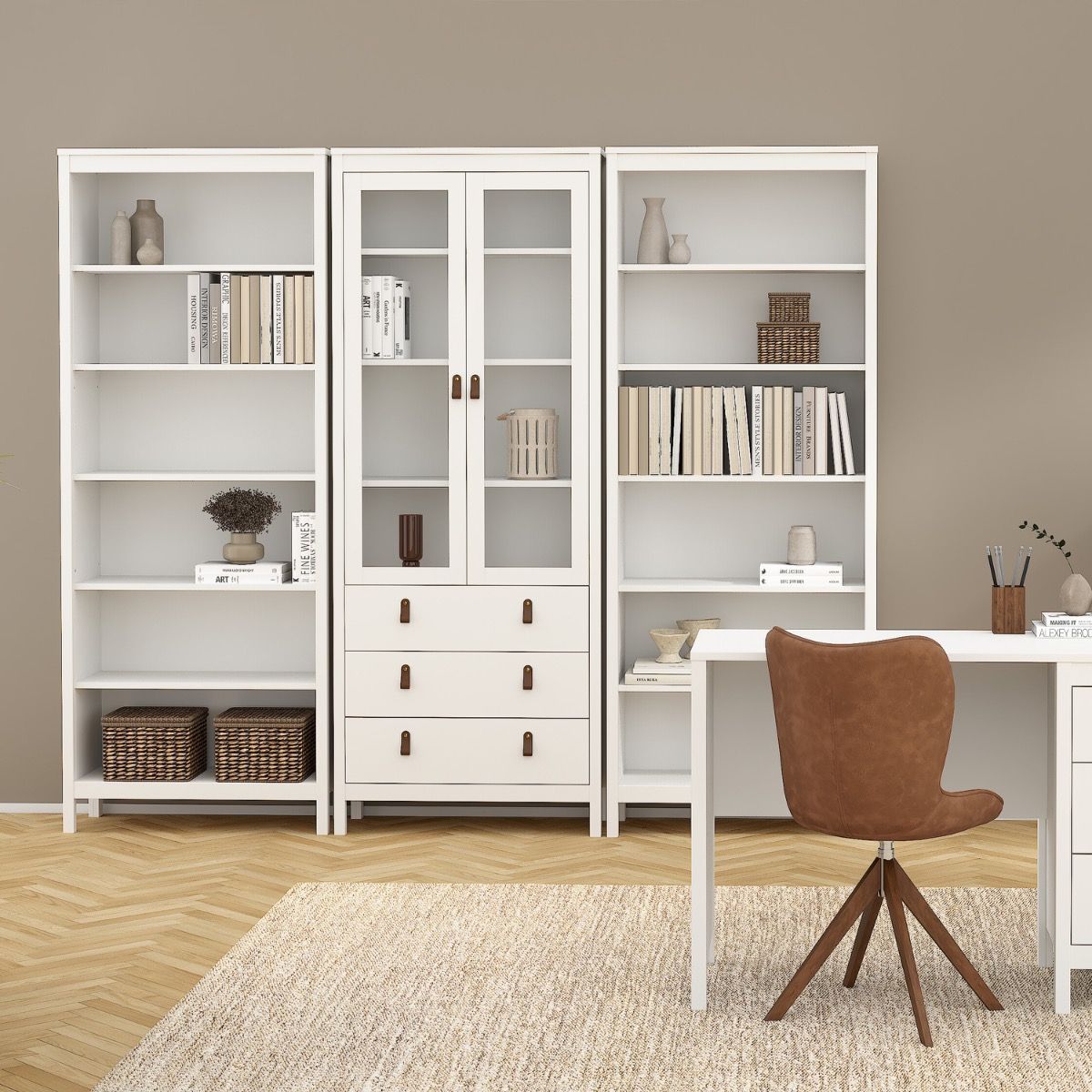A white wooden home office furniture set including a tall bookcase with glass doors, open shelves, a desk, and a brown velvet swivel chair, arranged in a minimalist room with a beige wall and wood herringbone floor.