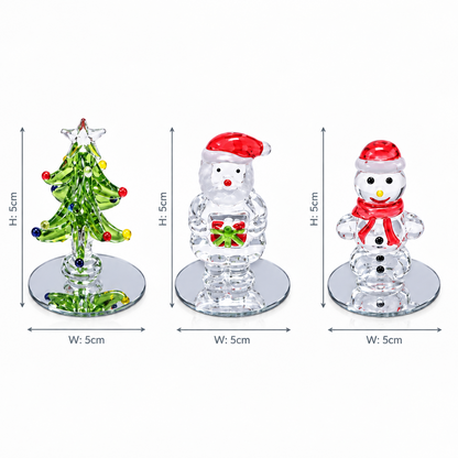 Three small holiday-themed glass figurines shown on a white background with dimension arrows and labels: a green crystal Christmas tree, a clear Santa in a red Santa hat holding a gift, and a clear snowman in a red Santa hat and scarf. Width and height measurements are printed beside each item.
