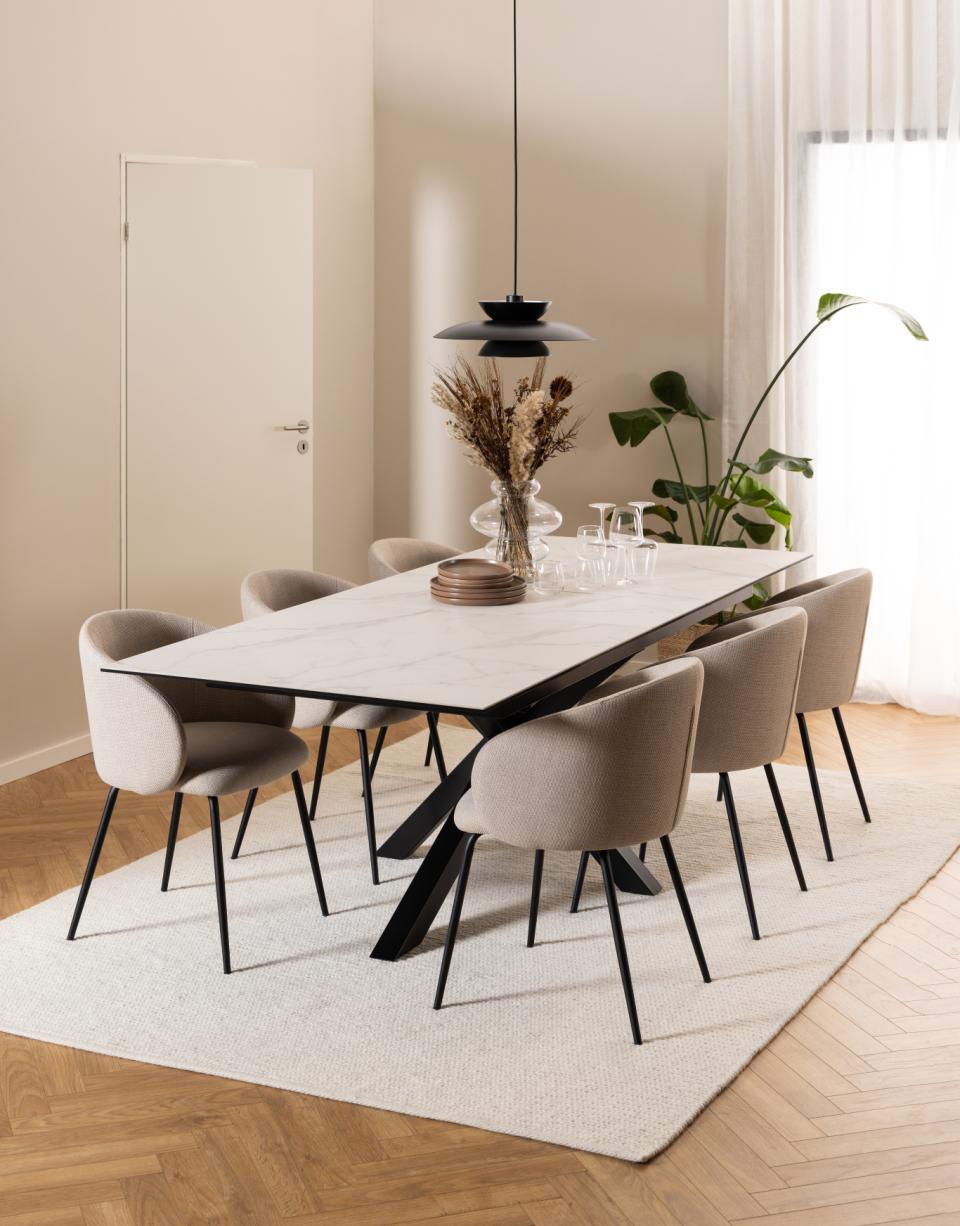 Modern dining room with a long white table and six gray chairs on a wooden floor.