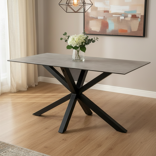 Dining table with black metal legs and a vase of flowers in a room with curtains and a painting.