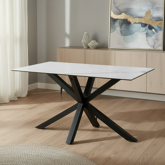 Modern dining table with black legs in a room with light wood flooring and a painting on the wall.