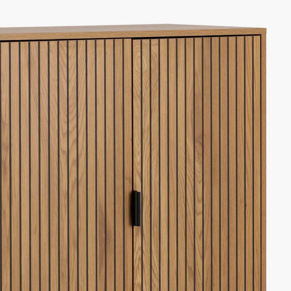 Wooden cabinet with vertical slats and a black handle on a white background