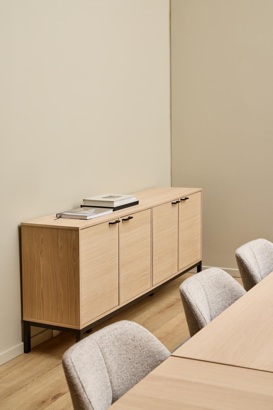 Light wood Kensington sideboard against a beige wall with gray chairs in front