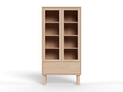 A light natural wood bookcase with two glass-front upper doors, four interior shelves, and a lower drawer, shown on a clean white background.