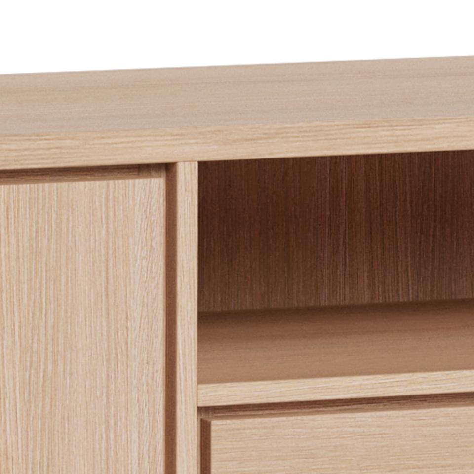 Close-up of a light oak wood sideboard showing a door panel, open shelf compartment, and drawer front against a white background.