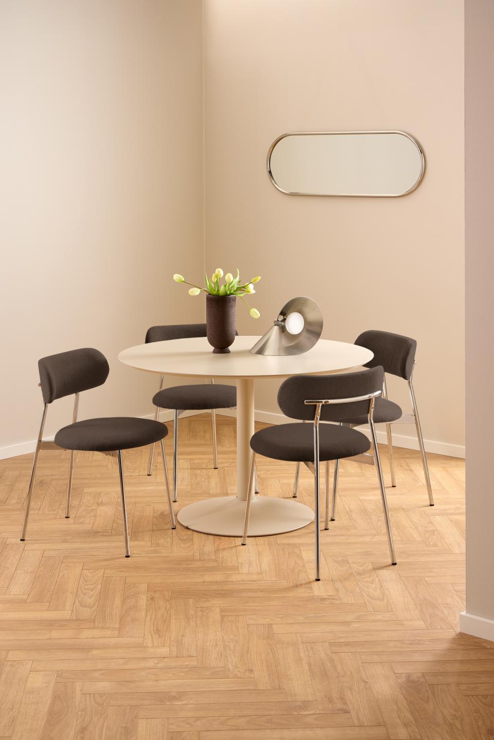 Dining area with a round table and four chairs on a wooden floor.