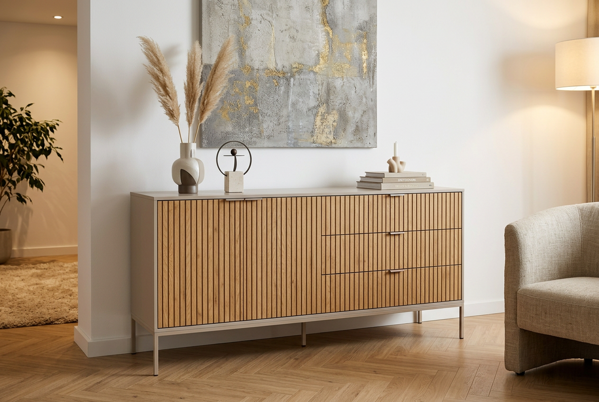 A large Seaford sideboard with grey frame and lamella oak wood front in a modern home with pampas on top, a large ap on the wall, a chair to the side and a plant in the background