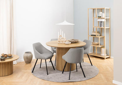 Dining room with round wooden table and gray chairs, wooden shelf, and light decor.