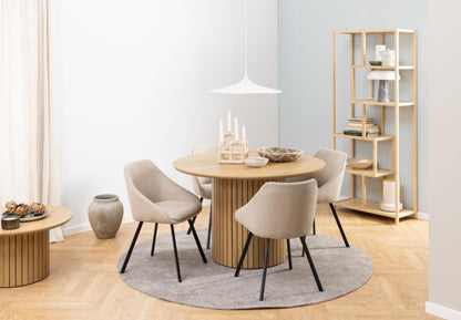 Dining room with round wooden table and chairs in a modern interior setting.