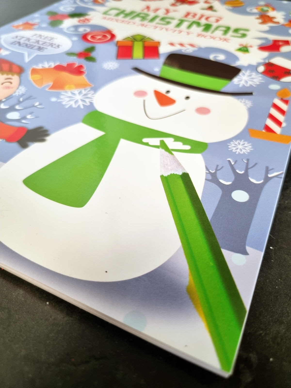 A close-up of a children's Christmas activity book cover featuring a snowman with a green scarf and top hat, surrounded by festive illustrations and the title 'My Big Christmas Activity Book.'.