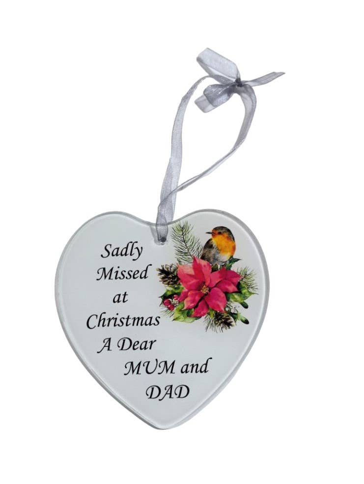 A heart-shaped white ceramic Christmas ornament hanging from a white ribbon, printed with the message 'Sadly Missed at Christmas A Dear MUM and DAD' all on a white background
