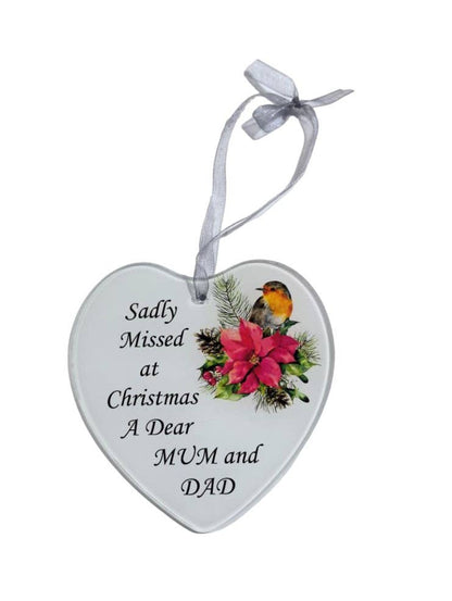 A heart-shaped white ceramic Christmas ornament hanging from a white ribbon, printed with the message 'Sadly Missed at Christmas A Dear MUM and DAD' all on a white background