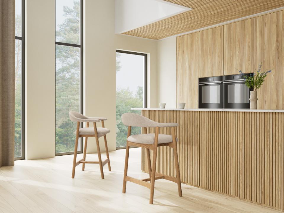 Modern kitchen with wooden cabinets, a island, and a pair of Addi bar stools.