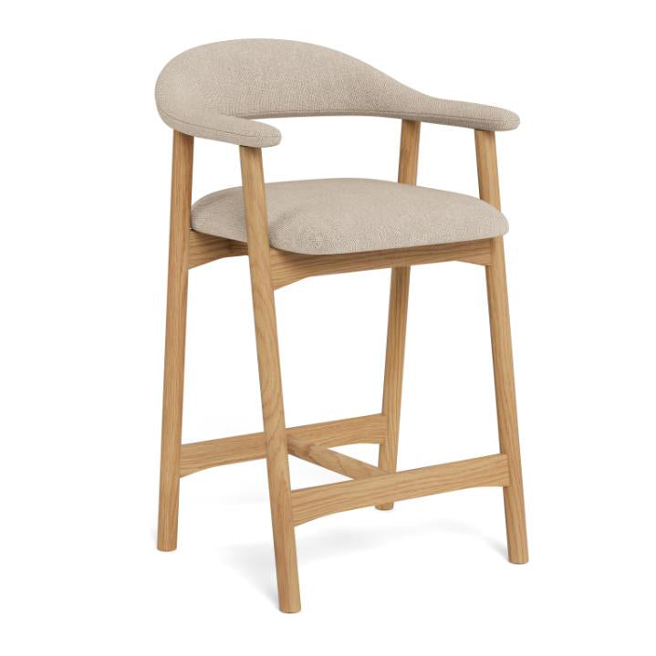 A modern bar stool with a light oak wood frame and a curved backrest, upholstered in a textured beige fabric, shown on a white background.