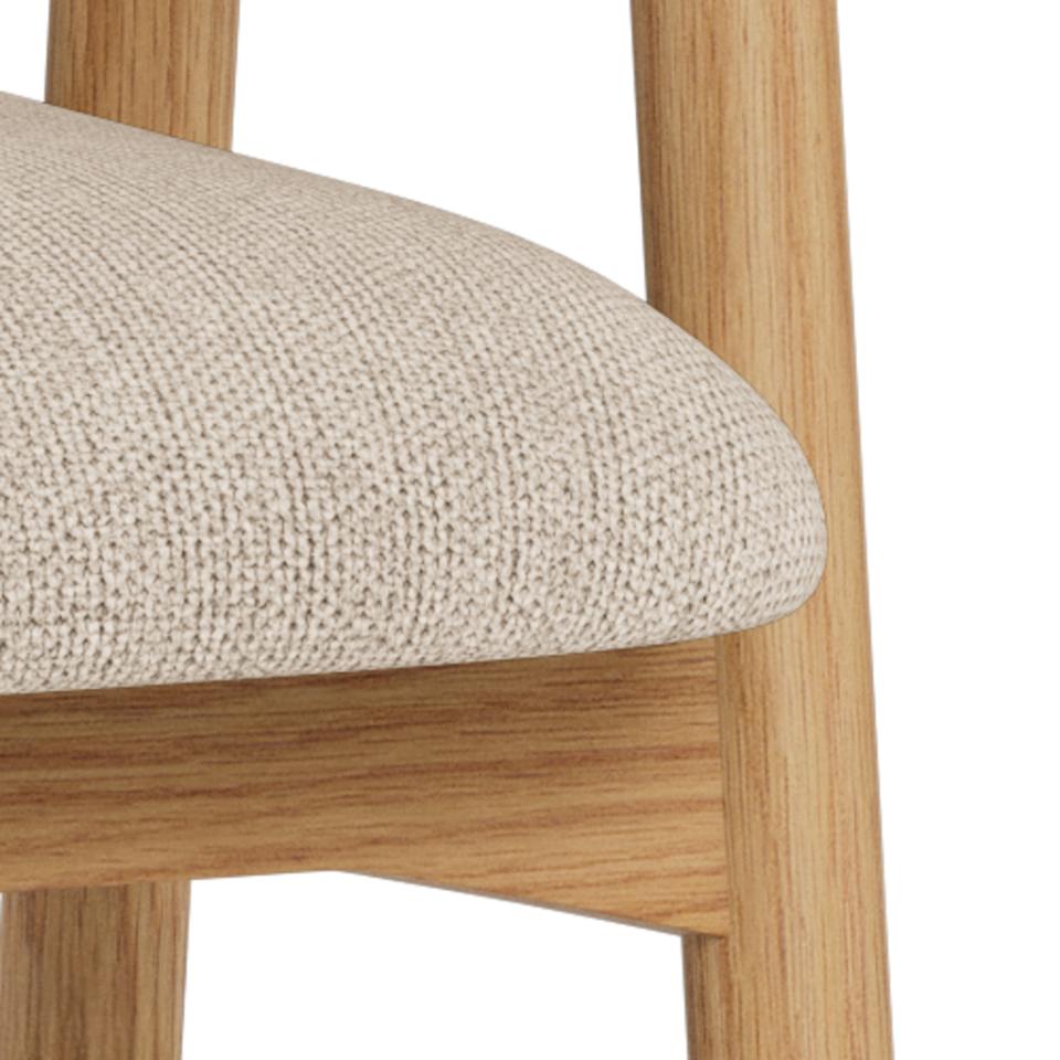 Close-up of a wooden chair with a beige fabric seat on a white background