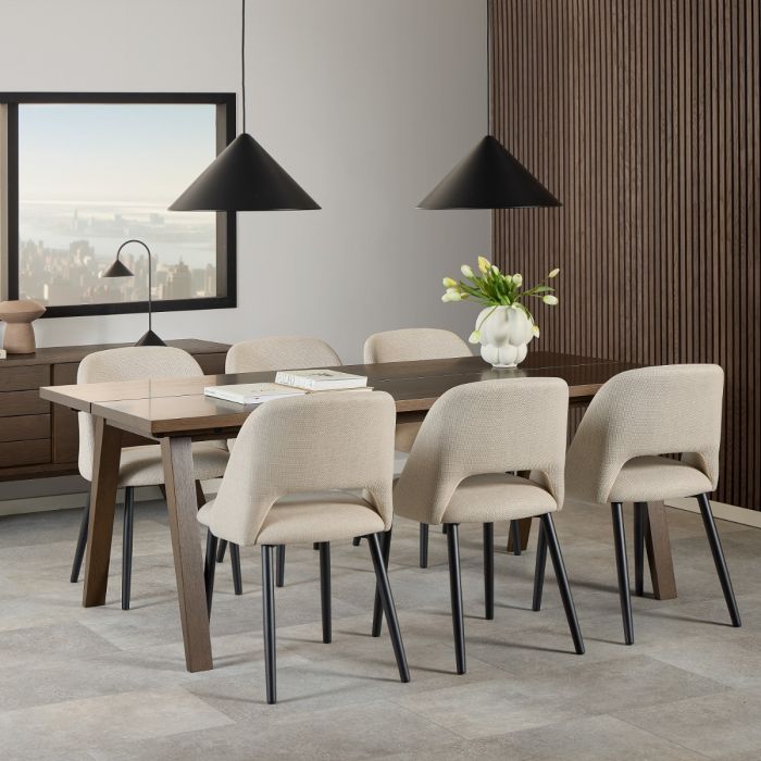 Dining room with a wooden table and beige chairs, featuring a vase of flowers on the table.