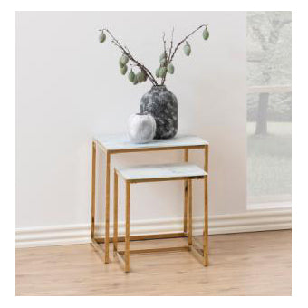 Two nested square nesting side tables with white marble-look tops and gold metal frames, styled with a dark textured vase and a small white pot on a light wood floor against a neutral wall.