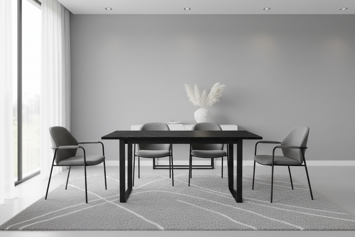 A modern dining room setup featuring a black rectangular table surrounded by four gray upholstered chairs with black metal frames, set on a light gray patterned rug against a minimalist gray wall.