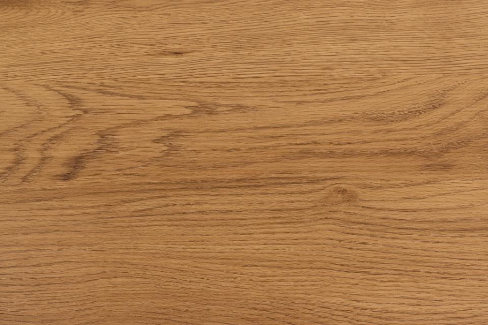 A close-up view of a warm medium-brown wood grain surface with visible natural texture and subtle tonal variation.
