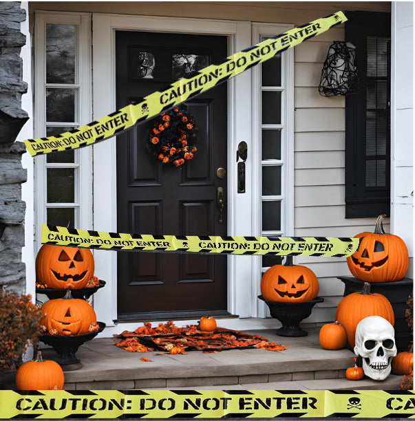 Halloween front porch decorated with orange pumpkins, jack-o'-lanterns, a skull, scattered autumn leaves, and yellow caution tape reading 'CAUTION: DO NOT ENTER' strung across the door.