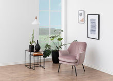 Load image into Gallery viewer, A modern pink velvet armchair with black metal legs in a bright, minimalist room with light wood floors, a large window, and framed wall art.
