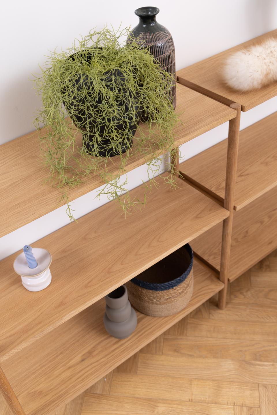 Wooden shelf with decorative items including a plant, vases, and a candle.
