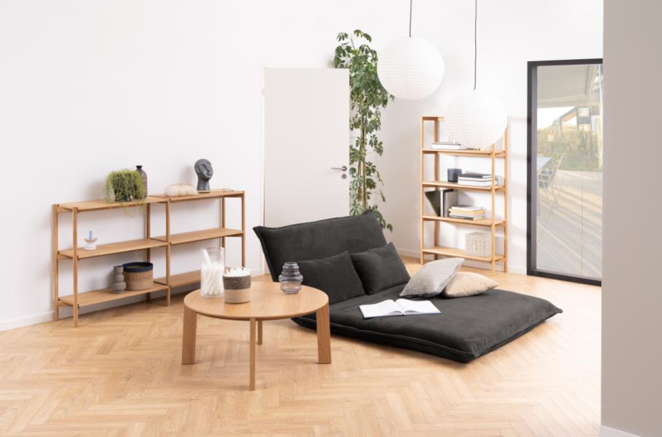 Modern living room with a black sofa, wooden coffee table, and shelves.